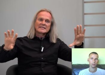 Erwachsener Talk-Gast bei D-Talk im Interview, auf einem schwarzen Sessel sitzend, im Gespräch, mit grauem Hintergrund, für Podcast und digitale Kommunikation.