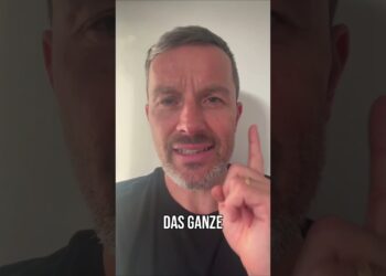 Eindeutiger, humorvoller Mann mit grauem Bart, der einen Finger hebt und den Satz "DAS GANZE" sagt, in einem weißen Hintergrund, geeignet für Motivations- oder Präsentationsvideos.